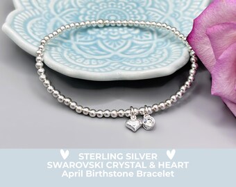 May include: A sterling silver beaded bracelet with heart and Swarovski crystal charms. The bracelet is displayed on a light blue decorative plate with a floral design. The text on the image reads "STERLING SILVER SWAROVSKI CRYSTAL & HEART April Birthstone Bracelet."