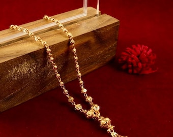 May include: A gold chain necklace with a decorative pendant. The chain is made of small, round beads and the pendant is a cluster of smaller beads with a tassel.