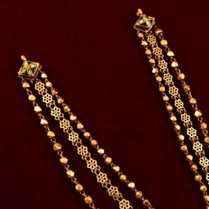 Peut inclure: Un collier en or compos&eacute; de trois rangs de cha&icirc;ne. Le rang central pr&eacute;sente un motif floral d&eacute;licat, tandis que les rangs ext&eacute;rieurs sont faits de perles rondes. Le collier a un pendentif carr&eacute; avec de l'&eacute;mail vert et blanc.