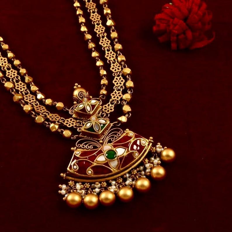 Peut inclure: Un collier en or avec une cha&icirc;ne &agrave; plusieurs rangs et un grand pendentif. Le pendentif est d&eacute;cor&eacute; d'&eacute;mail rouge, vert et blanc et pr&eacute;sente des motifs floraux complexes.