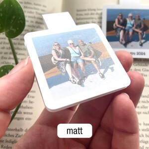Ein personalisierbares magnetisches Lesezeichen mit Urlaubsfoto wird so in die Kamera gehalten, dass die matte Oberfläche gut zu erkennen ist. Darunter steht in einem weißen Feld der Text „matt".