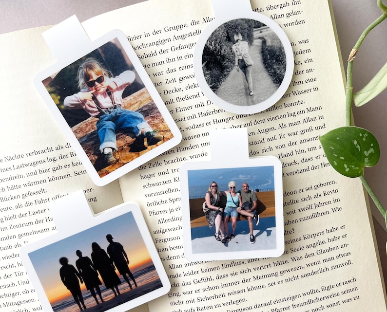 Auf einem aufgeklappten Buch liegen vier personalisierte Magnetlesezeichen in den Formaten rund, quadratisch, Quer- und Hochformat. Darauf zu erkennen sind persönliche Fotos von einzelnen Personen und Gruppen.