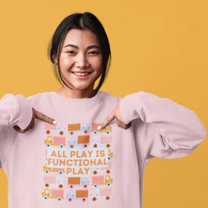 May include: A pink sweatshirt with a graphic design of toy trucks and the text "All Play is Functional Play".