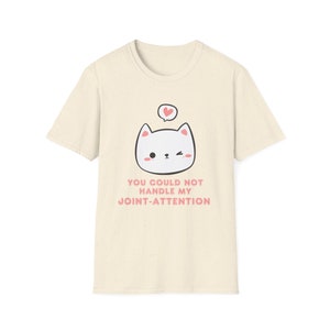 Puede incluir: Una camiseta beige con un gato de dibujos animados que lleva un corazón rosa sobre su cabeza. El texto "You could not handle my joint-attention" está impreso en rosa debajo del gato.