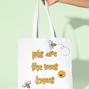 May include: White tote bag with the text "pts are the bees knees" in yellow lettering. There are two bee illustrations and a honeycomb illustration on the bag.