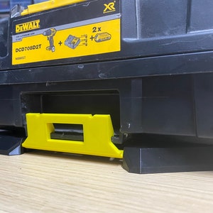 May include: A black and yellow DeWalt tool box with the model number DCD708D2T and the text "XR" printed on the side. The tool box has a black base with a yellow handle.