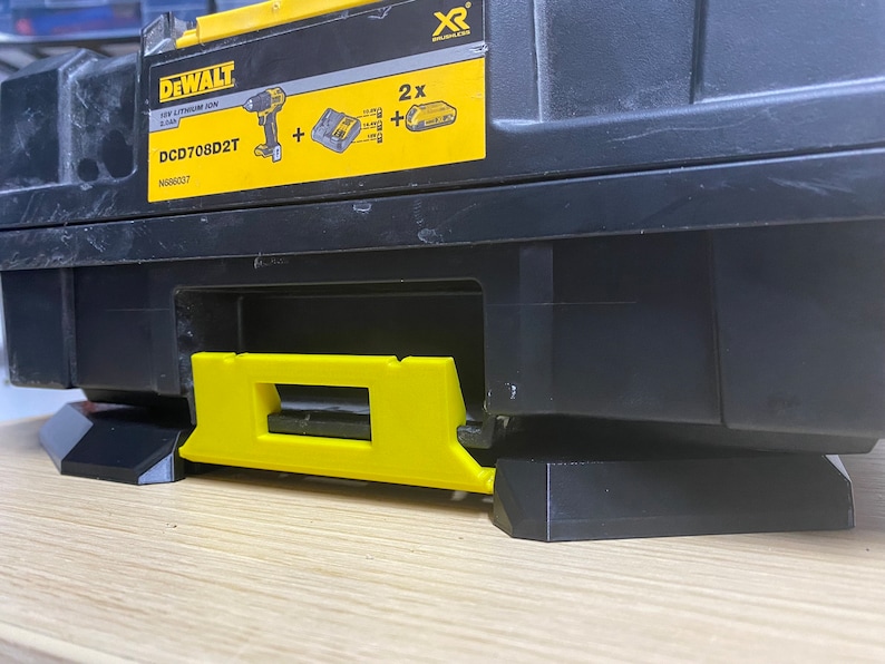 May include: A black and yellow DeWalt tool box with the model number DCD708D2T and the text "XR" printed on the side. The tool box has a black base with a yellow handle.
