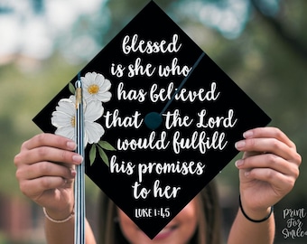 Könnte beinhalten: Schwarze Abschluss-Kappe mit weißen Blumen und dem Text "blessed is she who has believed that the Lord would fulfill his promises to her" und "LUKE 1:45".