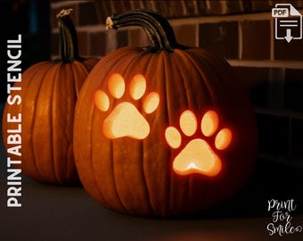 May include: Two orange pumpkins with carved paw print designs. The pumpkins are lit from within, creating a warm glow. The words "PRINTABLE STENCIL" are printed vertically on the left side of the image.