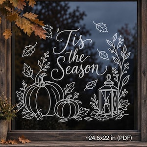 Op de afbeelding: Een witte vinyl raamsticker met de tekst 'Tis the Season' in elegant handschrift, omringd door lijntekeningen van twee pompoenen, een lantaarn met een kaars en herfstbladeren, met een afmeting van 24,6x22 inch.