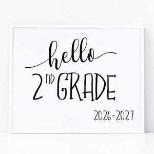 Könnte beinhalten: Ein rechteckiges weißes Schild mit schwarzem Text, der hello 2nd GRADE 2026-2027 lautet. Das Wort hello ist in Schreibschrift gehalten, während 2nd GRADE in einer fetten Schriftart steht. Unten rechts befindet sich der Text Print For Smile.