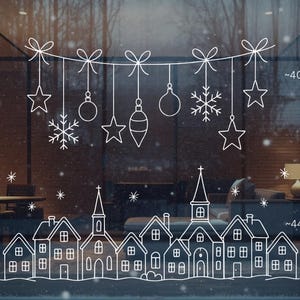 Puede incluir: Adhesivo de ventana de arte lineal blanco con adornos navideños, estrellas y copos de nieve colgando de lazos. Una escena de pueblo está en la parte inferior. El texto "PRINTABLE WINDOW ART" está en el lado izquierdo. Dimensiones aproximadas 102 x 43 cm y 112 x 43 cm.