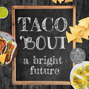 May include: A chalkboard sign with the text "Taco 'Bout a bright future" written in white chalk. The sign is surrounded by various taco-themed decorations, including a plate of tacos, a bowl of salsa, and a bowl of guacamole.