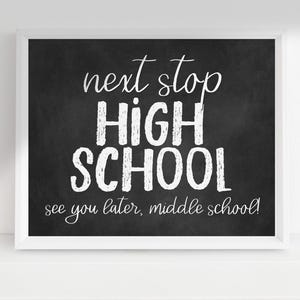 May include: A framed print with a chalkboard effect, featuring white text. The message says "next stop HIGH SCHOOL see you later, middle school!". The print is in a white frame, ideal for celebrating graduation or the start of high school.