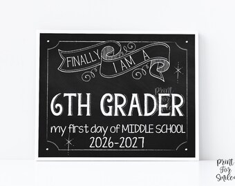 May include: A rectangular chalkboard sign with white hand-lettered text that reads FINALLY I AM A 6TH GRADER, my first day of MIDDLE SCHOOL, and 2026-2027. The design features a decorative banner at the top and star accents on a black background.