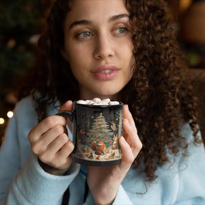 May include: A black ceramic mug with a winter forest scene featuring a Christmas tree, animals, and a red cardinal. The mug is filled with a hot beverage and marshmallows.
