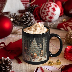 May include: Black ceramic mug with a winter forest scene featuring a decorated Christmas tree, animals, and a starry night sky. The mug is filled with a creamy beverage topped with whipped cream.