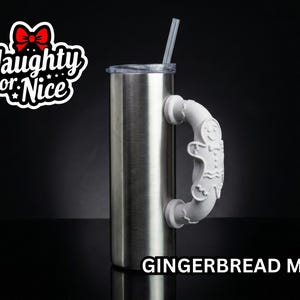 Puede incluir: Un vaso de acero inoxidable con tapa transparente y pajita, con un asa blanca en forma de hombre de jengibre. El texto Naughty or Nice aparece arriba a la izquierda y el texto GINGERBREAD MAN está abajo a la derecha.