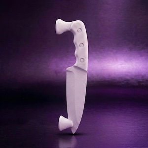 May include: A matte white knife featuring a curved handle with three circular indentations and a pointed blade. The knife is positioned vertically, with a small flared base at the top and a matching flared support at the bottom tip.