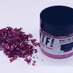 May include: A small jar of pink metallic foil flakes labeled "WTF! What The Flake Metallic Foil Flakes Rosie".