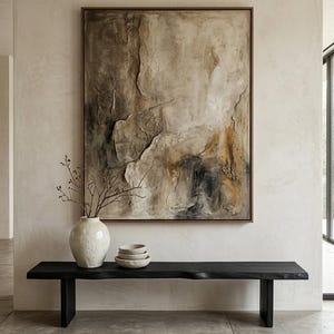Può includere: Un grande dipinto astratto in una cornice di legno marrone è appeso sopra una panca di legno nera. Un vaso bianco con rami e tre piccole ciotole sono sulla panca. Il dipinto presenta toni terrosi strutturati.