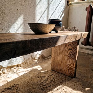 Könnte beinhalten: Ein rustikaler Holztisch mit natürlicher Oberfläche, auf dem sich zwei Keramikschalen befinden. Eine Schale ist hellbraun mit strukturierter Oberfläche, die andere dunkelblau. Der Tisch steht in einem sonnigen Raum.