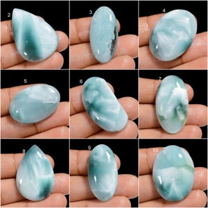 May include: Ten oval-shaped cabochon gemstones with a blue and white marbled pattern. The stones are arranged in three rows of three, with one stone in the center row. The stones are all approximately the same size and shape.
