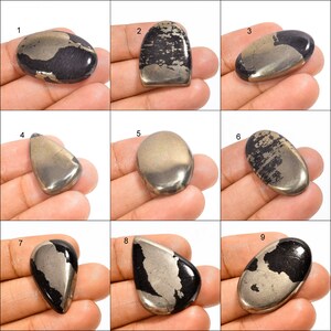 May include: Nine cabochon cut pyrite gemstones, each with a unique shape and size. The stones are a mix of black and gold with a metallic sheen.