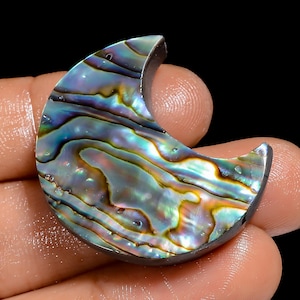 May include: A crescent moon shaped piece of abalone shell with iridescent blue, green, and gold colours.