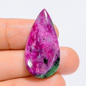Peut inclure: Une pierre précieuse en cabochon en forme de larme avec un motif de couleur rose et vert. La pierre précieuse a une surface lisse et polie.