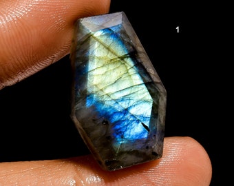 May include: A faceted, iridescent labradorite gemstone with a blue and green color scheme. The gemstone is shaped like a teardrop and has a smooth, polished surface.