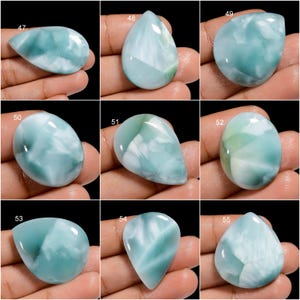May include: Ten cabochon gemstones, each with a unique pattern of blue and white, are displayed on a hand. The gemstones are labeled with numbers 47 through 55.