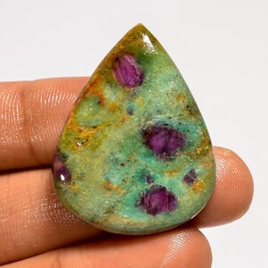 May include: A teardrop-shaped gemstone with a green base colour, featuring vibrant purple inclusions. The stone has a polished surface with hints of orange and brown, creating a unique and natural appearance. This gemstone is ideal for jewellery making.