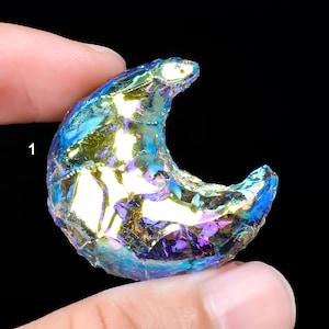 May include: A crescent moon shaped iridescent crystal with blue, green, and purple hues.