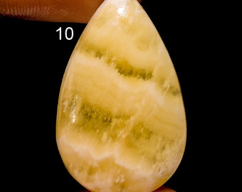 May include: A yellow and white banded agate cabochon with a teardrop shape. The stone has a smooth, polished surface and is approximately 1 inch in length.