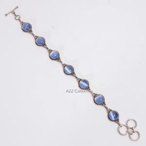 May include: A silver bracelet with a toggle clasp and seven blue cabochon stones.