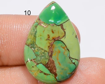 May include: A teardrop-shaped green turquoise cabochon with copper inclusions. The stone has a smooth, polished surface and a variety of green hues.