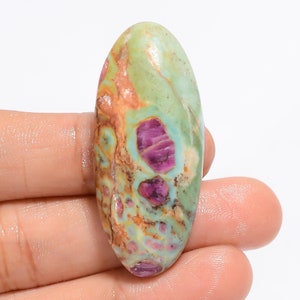 Peut inclure: Pierre précieuse ovale en cabochon avec un motif vert, brun et rose. La pierre a une surface lisse et polie.