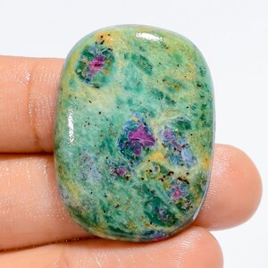 Peut inclure: Un cabochon de zoïsite rubis vert, jaune et rose avec une surface lisse et polie.