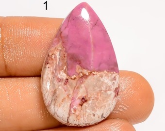 May include: A teardrop-shaped gemstone with a vibrant pink top and a textured, light-colored base. The stone has a polished surface and displays natural veining. The number "1" is visible in the upper left corner.