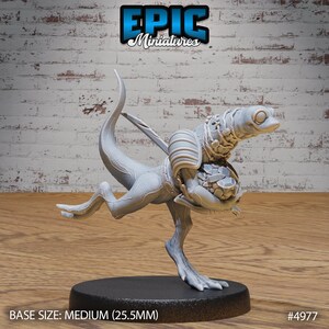May include: A gray 3D printed miniature of a lizard-like creature with a large head and a bag of gems in its hands. The miniature is standing on a round base. BASE SIZE: MEDIUM (25.5MM) #4977