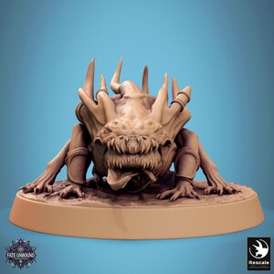 May include: A detailed miniature of a monstrous creature with a toothy maw, sharp claws, and a spiky, horned head. The creature is painted in a light brown colour and is posed in a menacing stance. The miniature is set on a circular base.
