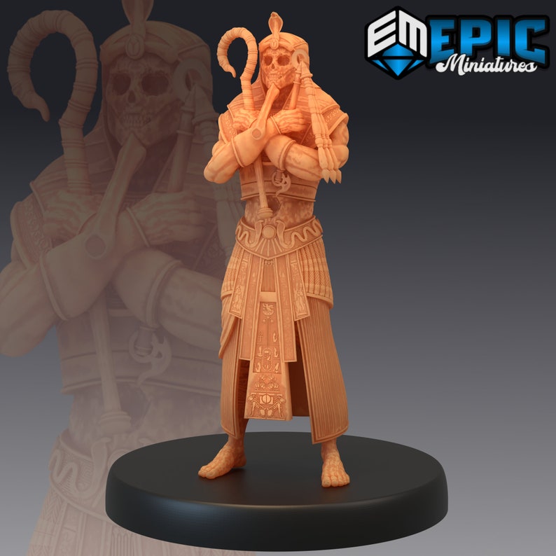 May include: A detailed miniature figurine of an Egyptian god, painted in a light brown color. The figure is wearing a traditional headdress and holding a staff. The figure is standing on a black base.