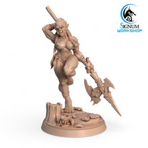 Op de afbeelding: Een gedetailleerd miniatuurbeeldje van een vrouwelijke orc-krijger, gebeeldhouwd in een naakte pose, met een speer met een bijlkop in de hand. Het beeldje staat op een voetstuk met een boomstronk en andere details.
