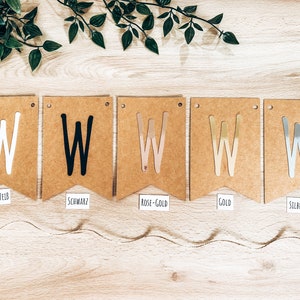 May include: Five brown paper pennant flags with the letter "W" in different colors. The flags are labeled "WEISS", "SCHWARZ", "ROSE-GOLD", "GOLD", and "SILBER".