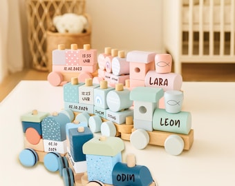 May include: Wooden toy train sets in pastel colors, including pink, blue, and green. Each train car features personalized details like names, dates, and times. The trains are on a white surface, with a wicker basket and crib in the background.