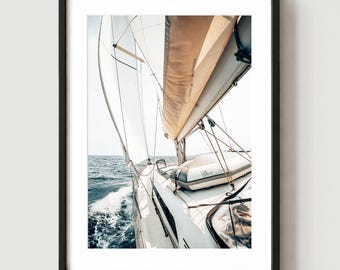 May include: A framed wall art print featuring a low-angle view of a white sailboat deck in motion. The image captures white sails catching the wind, a small inflatable dinghy secured on the deck, and deep blue ocean water with white sea foam.