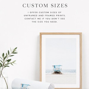 May include: A framed print of a lifeguard tower on a sandy beach with a light blue roof. A rolled print with the same image is in front of the frame. Text at the top says "CUSTOM SIZES".