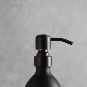 May include: Black soap dispenser with a copper-toned pump and a black glass bottle.