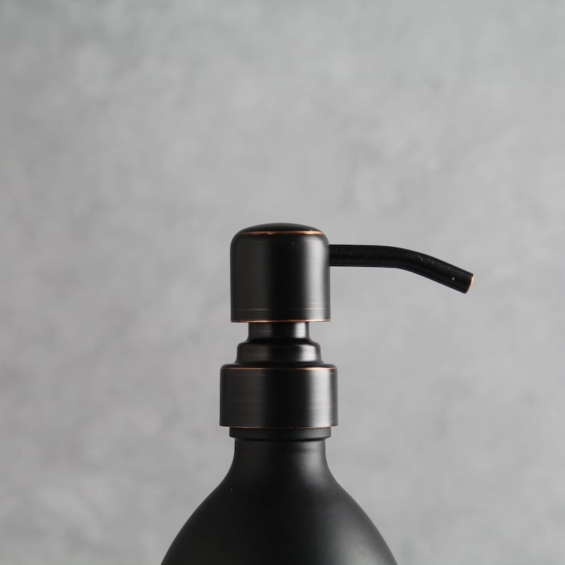 May include: Black soap dispenser with a copper-toned pump and a black glass bottle.